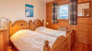 A wooden cabin room with two beds, a window with curtains, a painting on the wall, and a bedside lamp. - Ski-in/ski-out apartment, 4 bedrooms, 8 ppl, covered parking, WiFi (Les Arcs 1800)