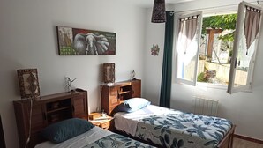 A bedroom with two beds, a wooden dresser, a nightstand, a wall-mounted artwork, and a window with curtains. - Logement Calme et Spacieux Avec vue à 400 M D'un Plan D'eau (Lamastre)