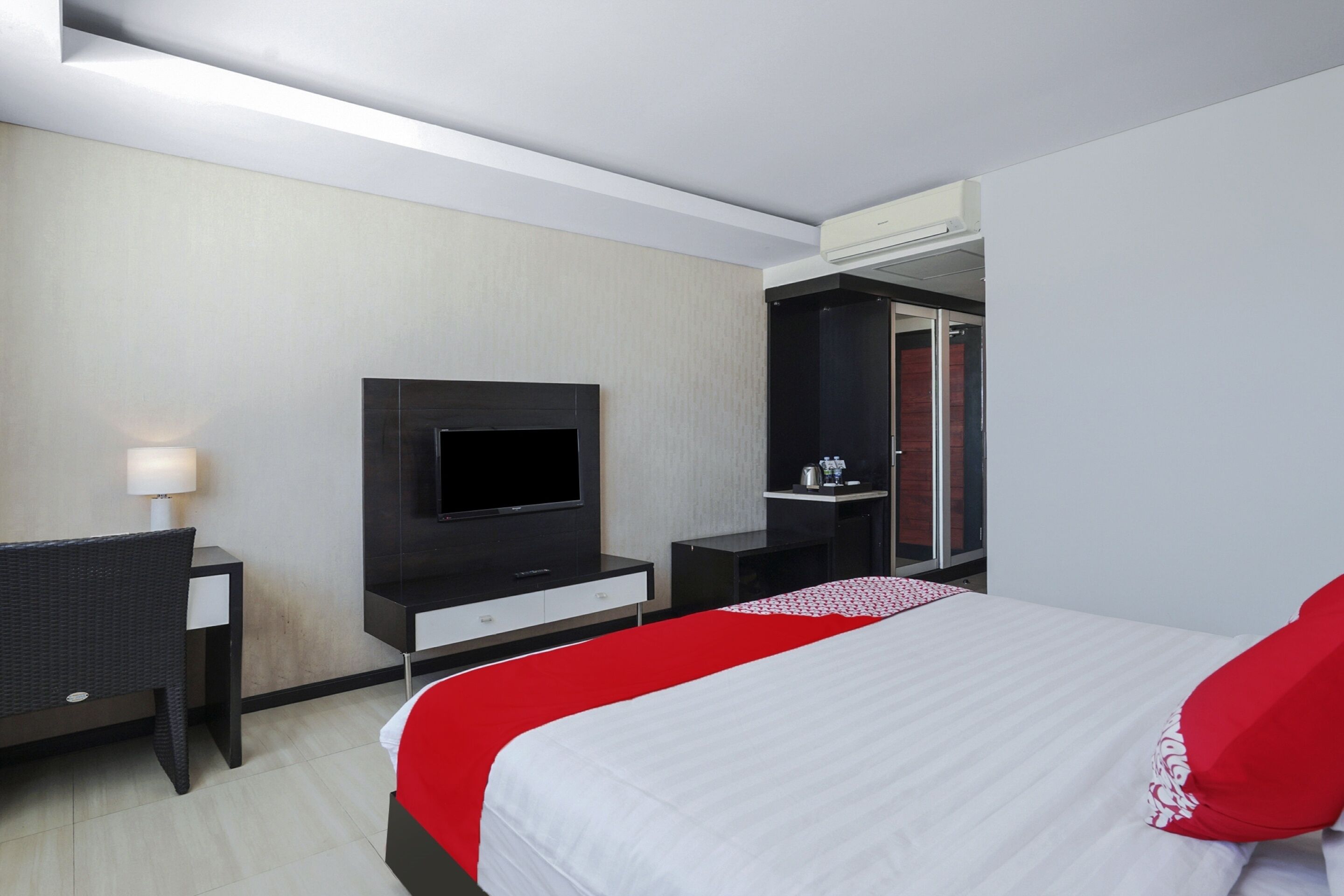 A modern hotel room with a large bed, a flat-screen TV, a desk, and a wardrobe.