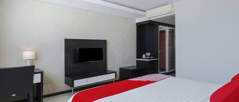 A modern hotel room with a large bed, a flat-screen TV, a desk, and a wardrobe.