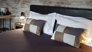 Un lit avec des oreillers blancs et à rayures, une tête de lit noire et une lampe sur une table de chevet.