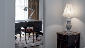 A bedroom with a bed, a desk with a chair, a lamp, and a small cabinet. - Villa Ayghedzor (Yerevan)