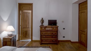 A bedroom with a bed, a wooden dresser, a television, and a lamp. - Villa Ayghedzor (Yerevan)