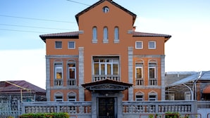 A two-story building with a symmetrical facade, large windows, and a central entrance with a decorative canopy. - Villa Ayghedzor (Yerevan)