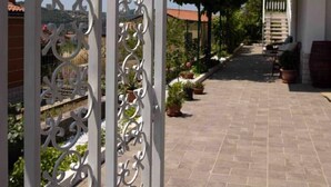 Ein Innenhof mit einem verzierten Metallgitter, Blumentöpfen und einem Gebäude mit einem Balkon.