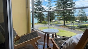 Enjoy a serene view of the park and water from this balcony, featuring a comfortable seating area with two chairs and a table.
