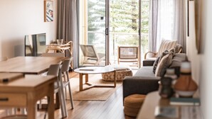 Amplia sala de estar con mesa de comedor de madera, sillas, sofá y un ventanal con vistas a zonas verdes.