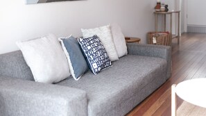 Relax in this stylish living room with a comfortable sofa, wooden floor, and natural touches.