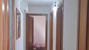 A hallway with tiled flooring, wooden doors, and a ceiling light fixture.