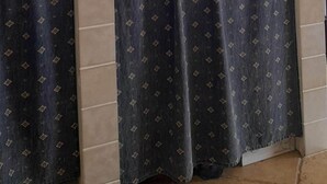 A kitchen with a tiled backsplash, a microwave, and a window with curtains.