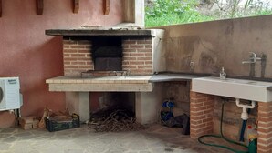 A kitchen with a brick oven, a sink, and a window with a view of greenery.