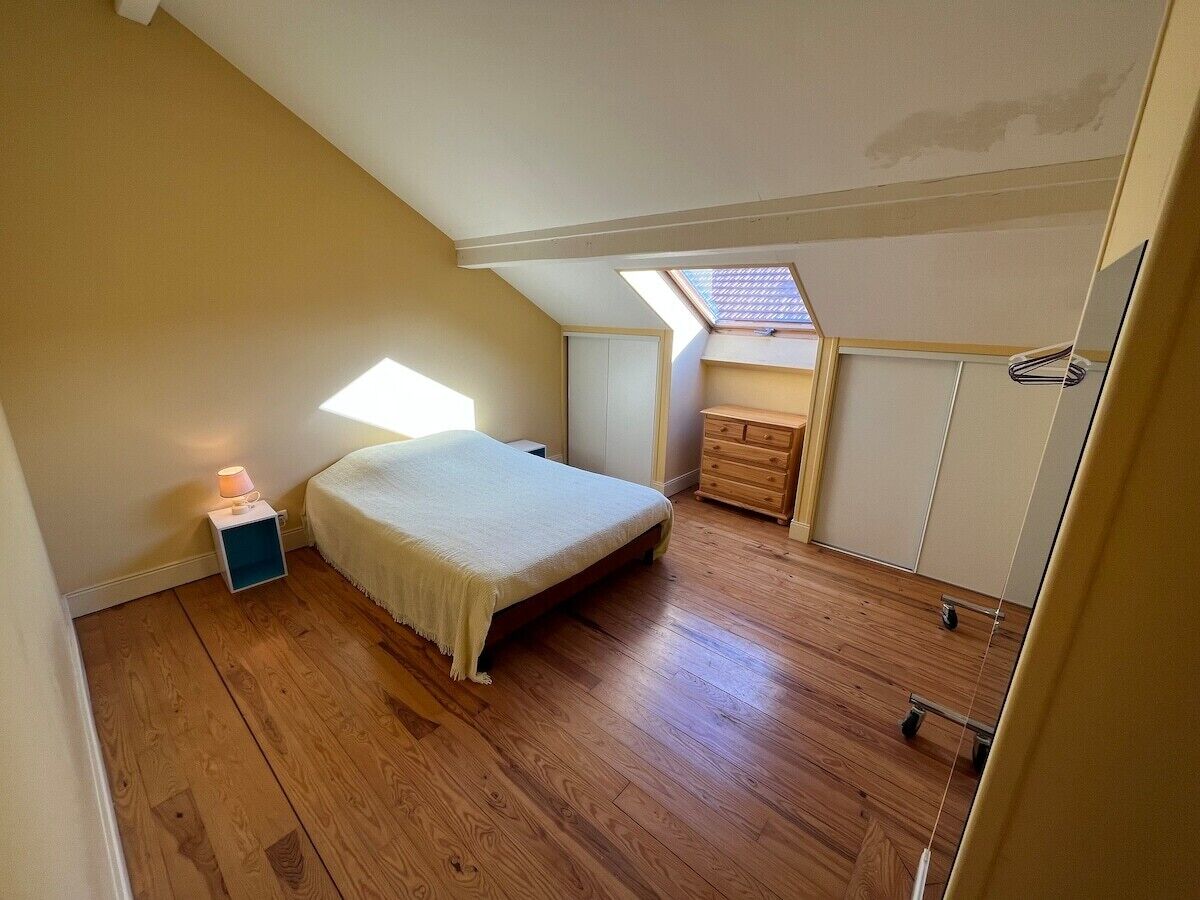 A bedroom with a bed, a nightstand, a dresser, and a skylight.