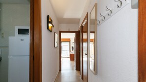 A hallway with a refrigerator, a microwave, and a door with hooks. - AirCon Apartment close to the Beach - UHC MAR Y LUZ (Salou)