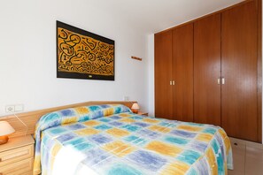 A bedroom with a bed, wooden wardrobe, and a wall-mounted artwork.