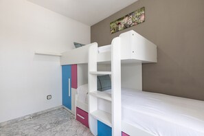 A bunk bed room with a marble floor, a small shelf, and a painting on the wall.