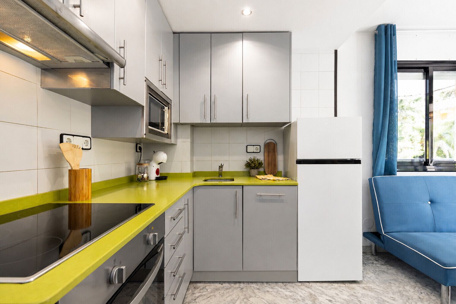 Una cocina moderna con armarios grises, una encimera amarilla y una silla azul.