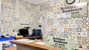 Uma mesa de recepção com parede estampada, um relógio e uma placa para Brilliant Residence.