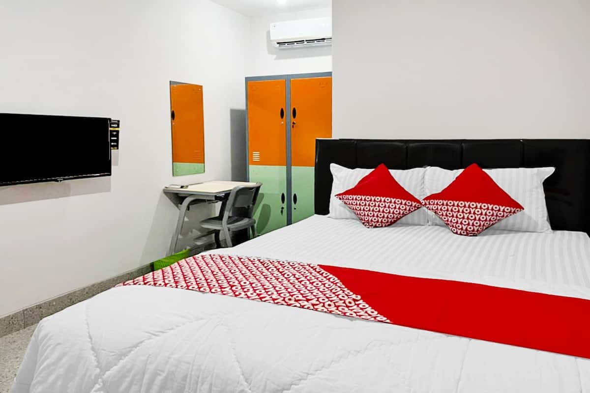 A hotel room with a bed, a desk, a chair, and a wardrobe.