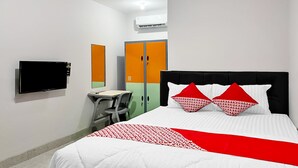 Quarto de hotel com cama, escrivaninha e televisão.
