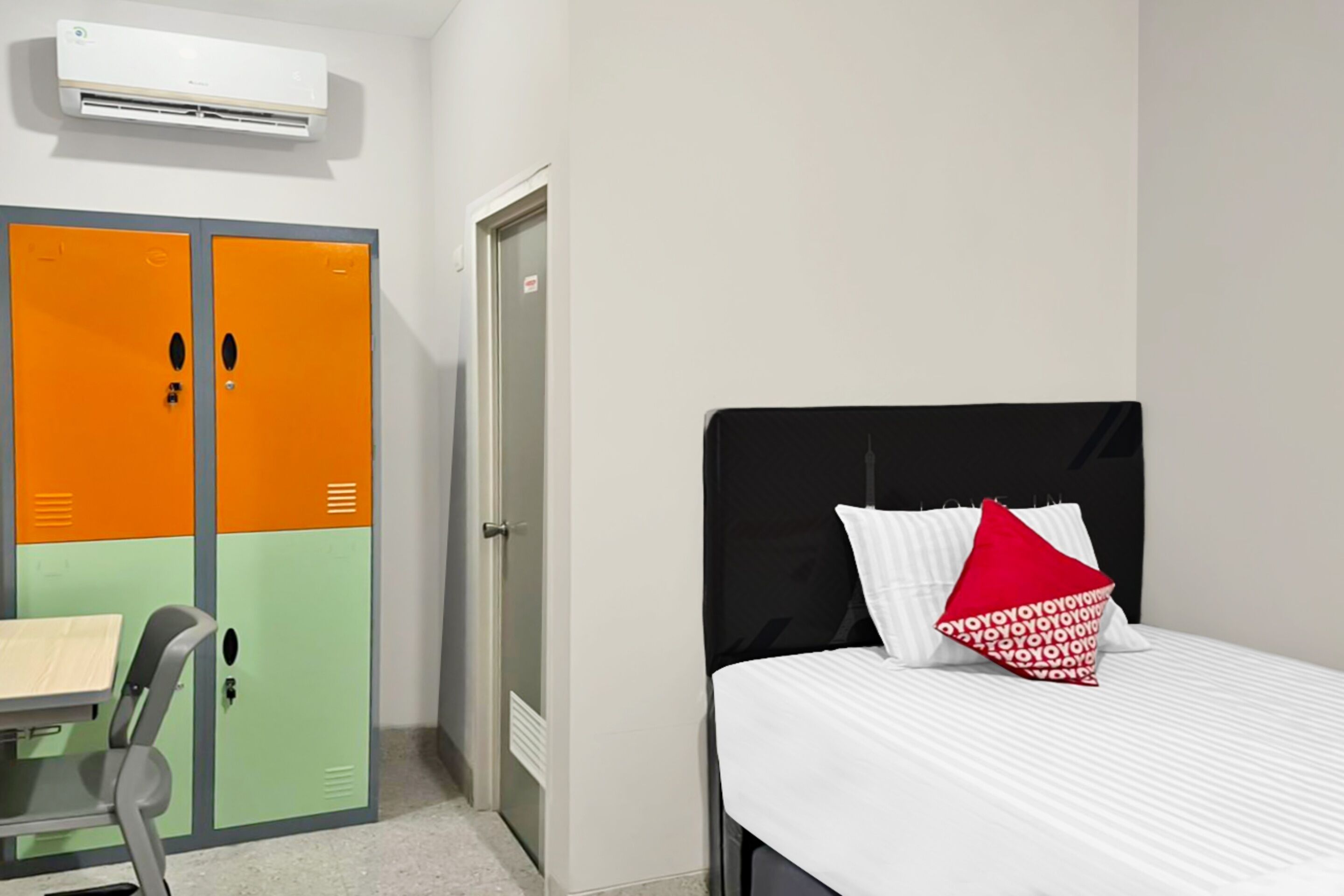 A room with a bed, a desk, and two lockers.