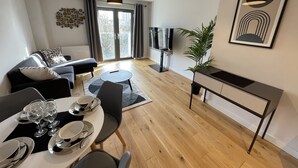 Een moderne woonkamer met een bank, eettafel en televisie.