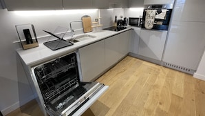 Een moderne keuken met grijze kastjes, een inbouwoven en een houten aanrecht.