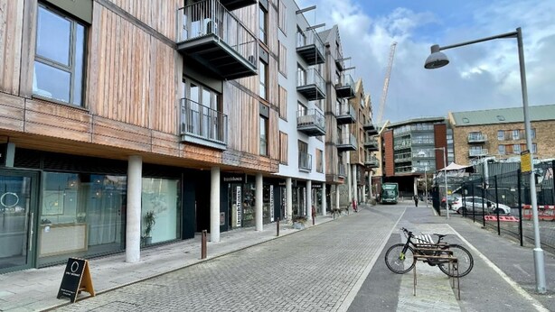 Een straat met moderne gebouwen, een fiets geparkeerd op het trottoir en een bouw kraan op de achtergrond.
