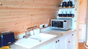 Una cocina con paneles de madera, armarios blancos, un lavamanos doble, un microondas y un tostador.