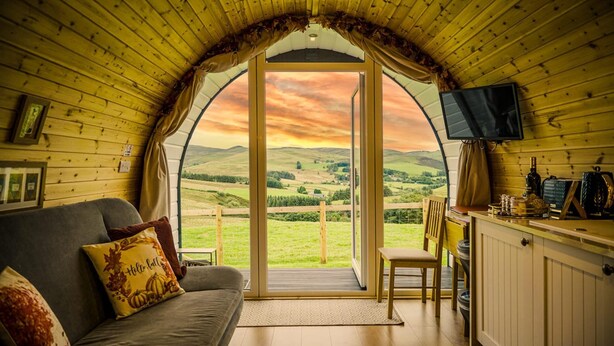 Una habitación acogedora con un amplio ventanal que ofrece una vista panorámica de colinas ondulantes.