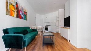A modern living room with a green sofa, a glass coffee table, and a dining area with a white table and chairs. - La Dolce Vita - Stylish Flat inTrastevere 60sqm (Roma)