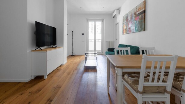 A modern living room with a flat-screen TV, a dining table with chairs, a sofa, and a painting on the wall. - La Dolce Vita - Stylish Flat inTrastevere 60sqm (Roma)