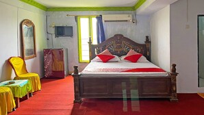 A bedroom with a wooden bed, a yellow chair, a table with a green tablecloth, and a mirror on the wall. - Hotel O Melati Bm Pangkep (Samalewa)
