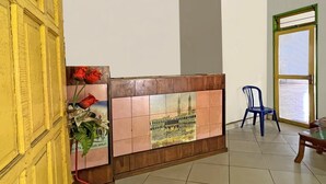 A reception area with a tiled wall, a wooden reception desk, a blue chair, and a window with a view of the outside. - Hotel O Melati Bm Pangkep (Samalewa)