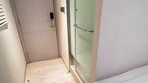 A narrow hallway with a wooden floor, a glass door, and a white wall. - POP E INN (Kowloon)