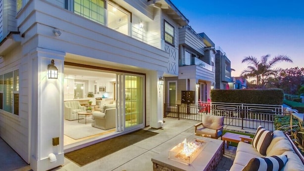 Une maison moderne dotée d’un vaste patio, d’un foyer extérieur et d’un intérieur bien éclairé.