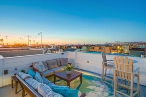 Eine Dachterrasse mit einer Couch, Stühlen und einem kleinen Tisch.