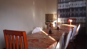Un comedor con una mesa cubierta por un mantel, rodeada de sillas de madera.