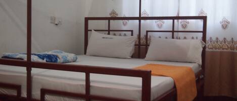 Una cama individual con estructura de madera, ropa de cama blanca y un dosel azul.