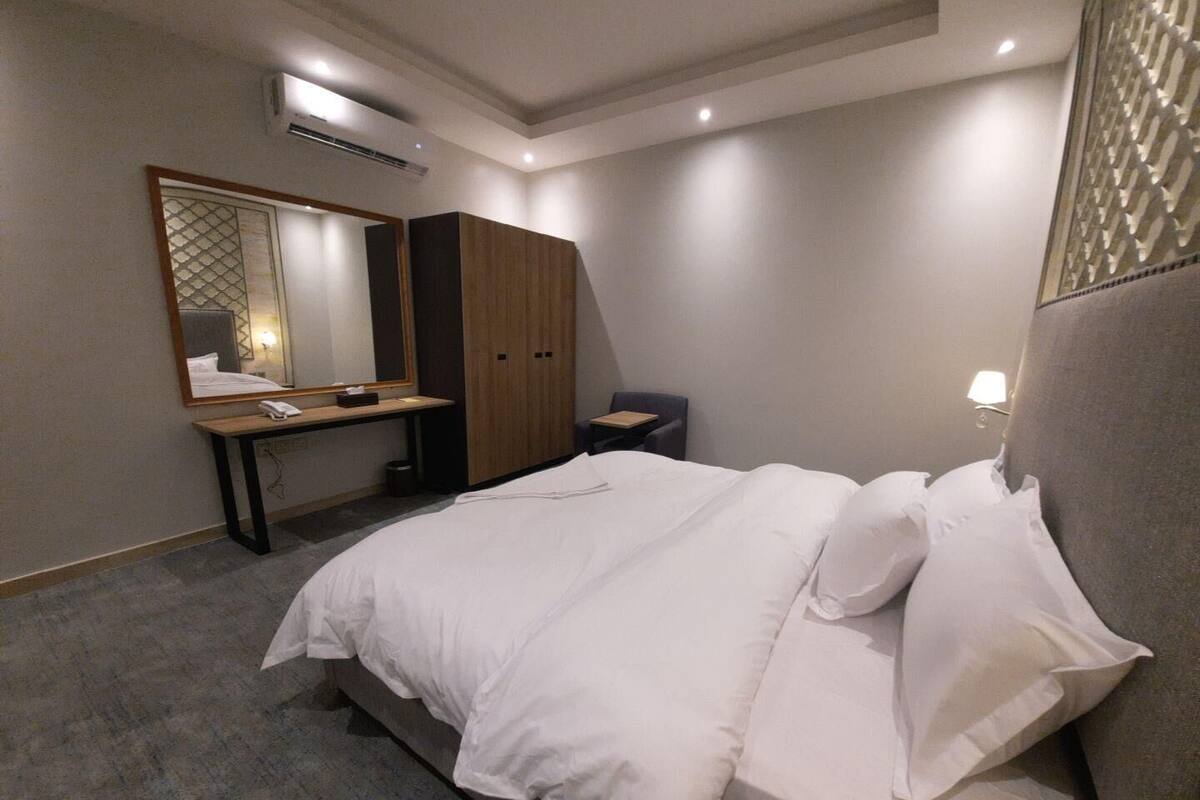 Une chambre d’hôtel moderne équipée d’un grand lit, d’un bureau avec une chaise, d’une armoire et d’un miroir.