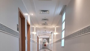 Un largo pasillo bien iluminado con suelo de mármol, paneles decorativos en las paredes y varias puertas que dan a diferentes habitaciones.