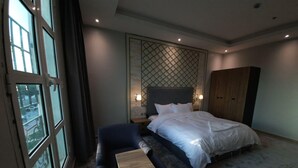 Una habitación de hotel con una cama grande, un sofá, una mesita de madera y un armario.