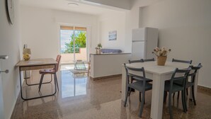 A modern kitchen with a dining area, a refrigerator, and a window with a view of greenery. - Erika House (Bova Marina)