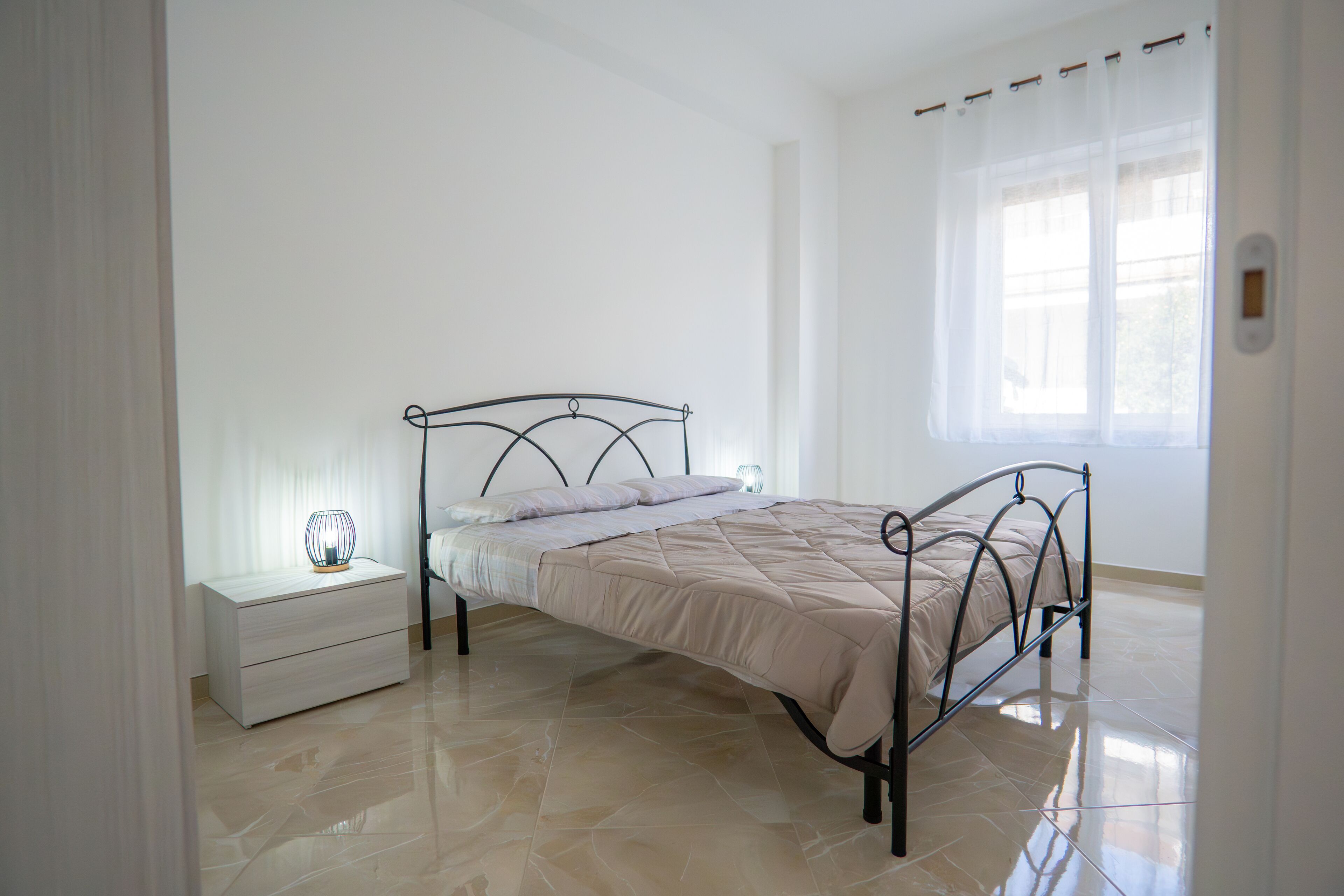 Una camera da letto con un letto, un comodino e una finestra con tende.