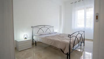 Una camera da letto con un letto, un comodino e una finestra con tende.