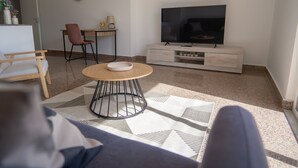 A living room with a sofa, a coffee table, a TV, a dining table, and a chair. - Erika House (Bova Marina)