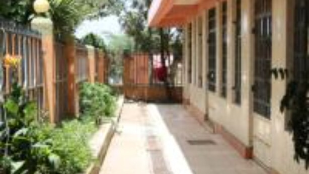 A corridor with a tiled floor, a bench, and a potted plant. - Maralink Hotel (Narok)