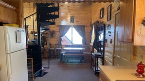 Een vakantiehuisje met houten inrichting, een eethoek en een keuken met koelkast en gootsteen.