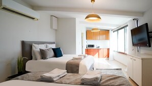 Ein modernes Hotelzimmer mit einem großen Bett, einem Flachbildfernseher, einer Küchenzeile und einem Essbereich.