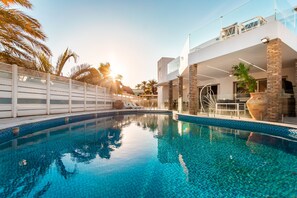 A modern pool area with clear blue water, a white fence, and a two-story building with a balcony. - YalaRent Villa Enorma with Private Pool (Eilat)