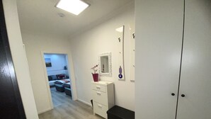 A hallway with a white door, a small desk with a mirror, and a potted plant. - Schöne Wohnung 72qm, Nähe Stadt- & Schulzentrum, 8 km von der Tschechei Entfernt (Selb)